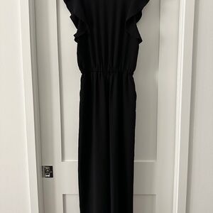Flowy black jumpsuit, open back with tie, pockets.